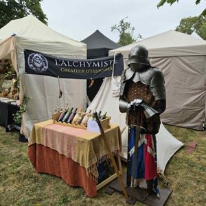 Armure médiévale et étal de bouteilles devant des tentes du festival Trolls & Légendes