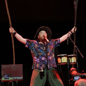 One Shot Bards - Un artiste enfiévré sur scène avec des percussions et des bâtons en bois.