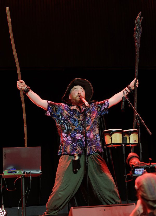 One Shot Bards - Un artiste enfiévré sur scène avec des percussions et des bâtons en bois.