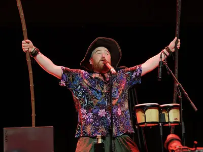 One Shot Bards - Un artiste enfiévré sur scène avec des percussions et des bâtons en bois.