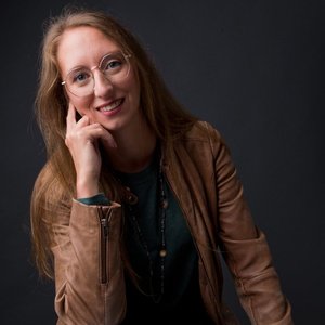 S.C BOYER - Portrait d'une femme souriante en veste en cuir sur fond noir.