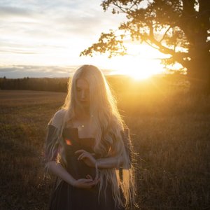 Sylvaine - Lueur dorée sur un champ au crépuscule avec une silhouette rêveuse.