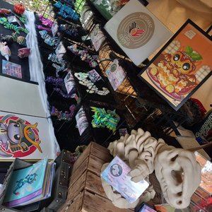 Stand d'artisanat coloré avec sculptures, affiches et bijoux fantastiques.