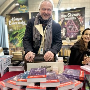 Editions Portejoie - Auteur souriant dédicaçant son roman fantastique au salon