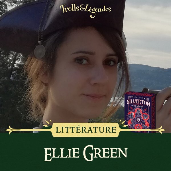 Ellie Green - Femme avec un chapeau, sourire, près d'une vue panoramique, livre "Silverton" à côté.