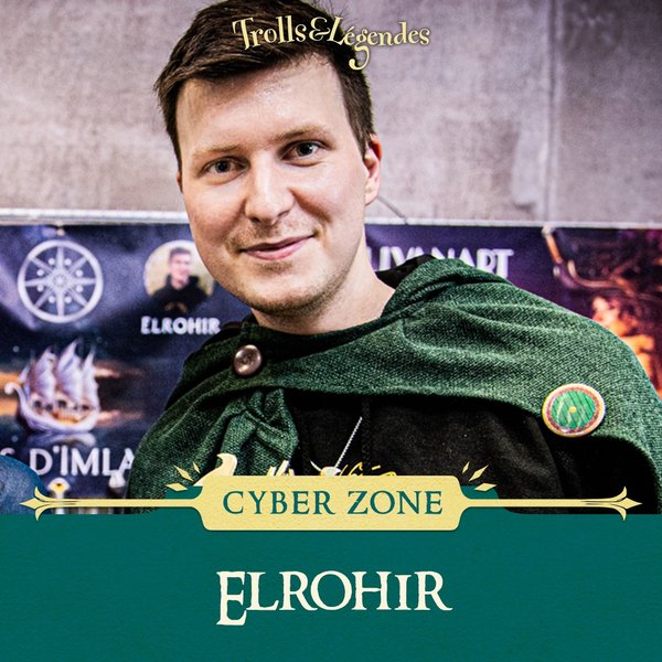 Elrohir - Homme souriant portant une cape verte, avec un fond de salon et le logo de Trolls & Légendes.