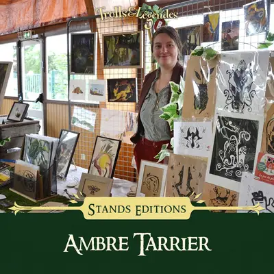 Ambre Tarrier - Femme souriante devant un stand de dessins et d'illustrations à Trolls & Légendes.
