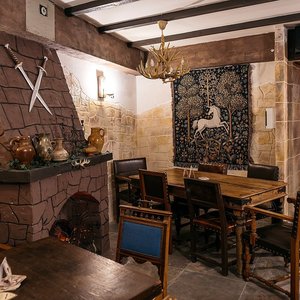 Njoy Games - Salle d'auberge médiévale avec cheminée, épées croisées et tapisserie à la licorne