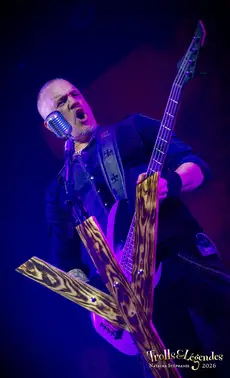 MANEGARN sur scène — hub: Concerts, évènement: Festival 2026. Guitare électrique au motif tiger géant, micro vintage, énergie brute et voix criée, éclairage bleu profond, ambiance rock live.