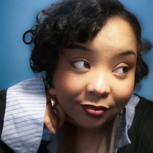 Debby EGG - Portrait élégant et expressif d'une femme au regard captivant sur fond bleu.