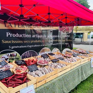 Étal de saucissons artisanaux sous barnum rouge au marché Trolls & Légendes.