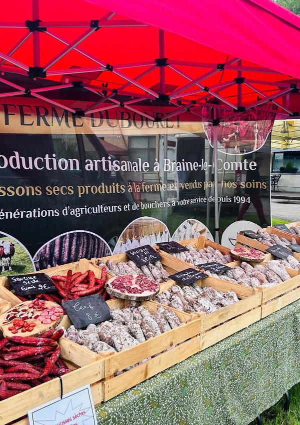Étal de saucissons artisanaux sous barnum rouge au marché Trolls & Légendes.