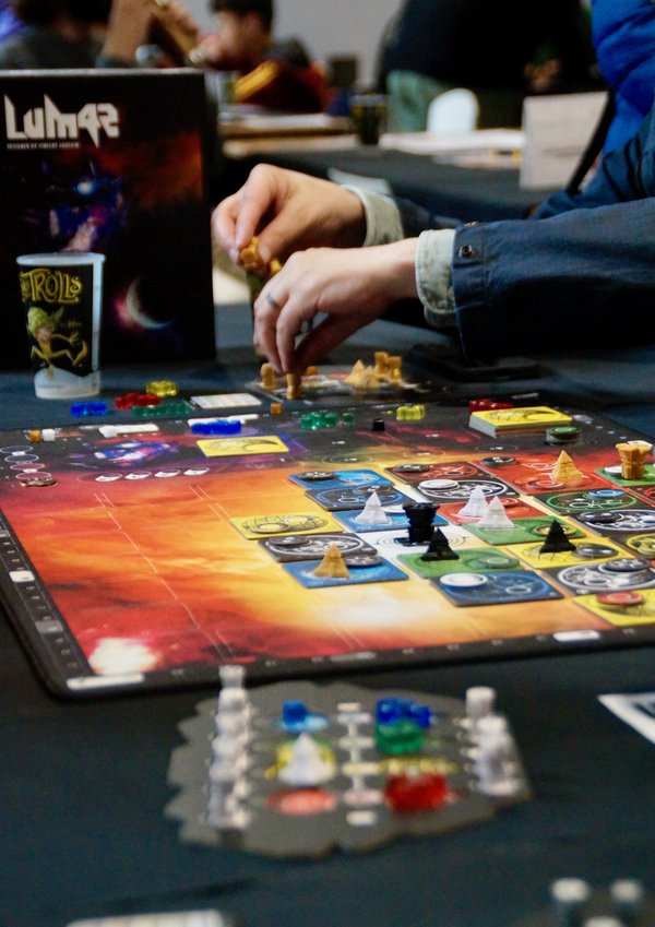 Personnes jouant à un jeu de plateau coloré sur une table lors d’un salon.