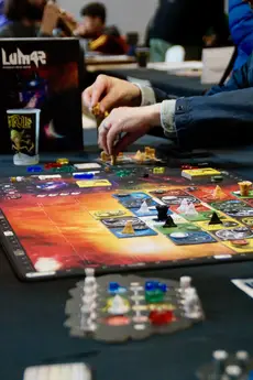 Personnes jouant à un jeu de plateau coloré sur une table lors d’un salon.