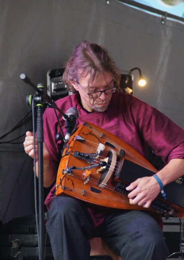 Musicien assis jouant de la vielle à roue sur scène, concentré.