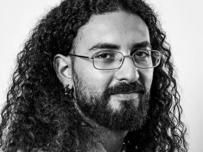 Pietrantonio BRUNO - Portrait en noir et blanc d'un homme aux cheveux bouclés et à lunettes.