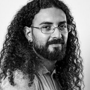 Pietrantonio BRUNO - Portrait en noir et blanc d'un homme aux cheveux bouclés et à lunettes.