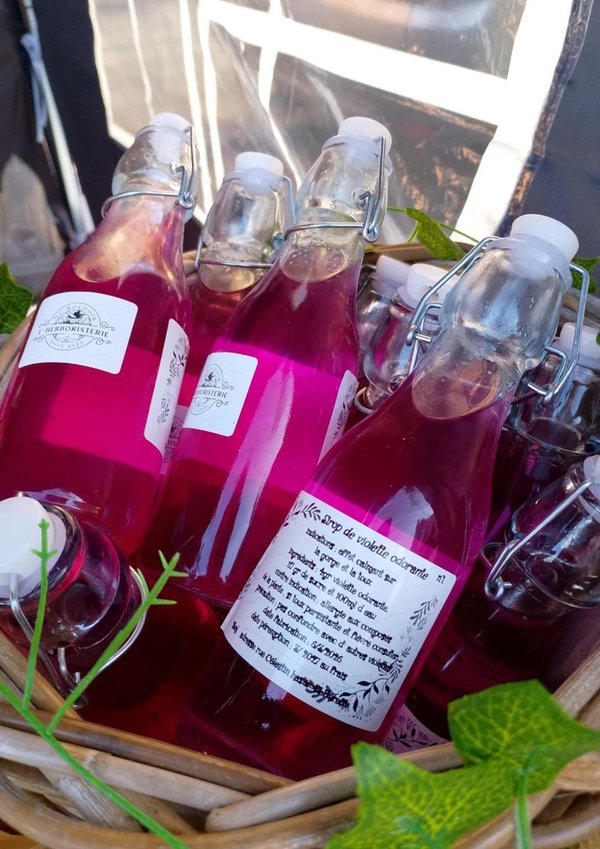 Bouteilles à fermeture mécanique contenant sirop rose vif disposées dans un panier décoré.