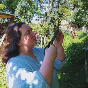 Femme coupant des fleurs blanches à l'extérieur, jardin verdoyant, atmosphère champêtre.