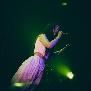 Kalandra - Une chanteuse envoûtante sur scène dans une ambiance lumineuse et mystérieuse.