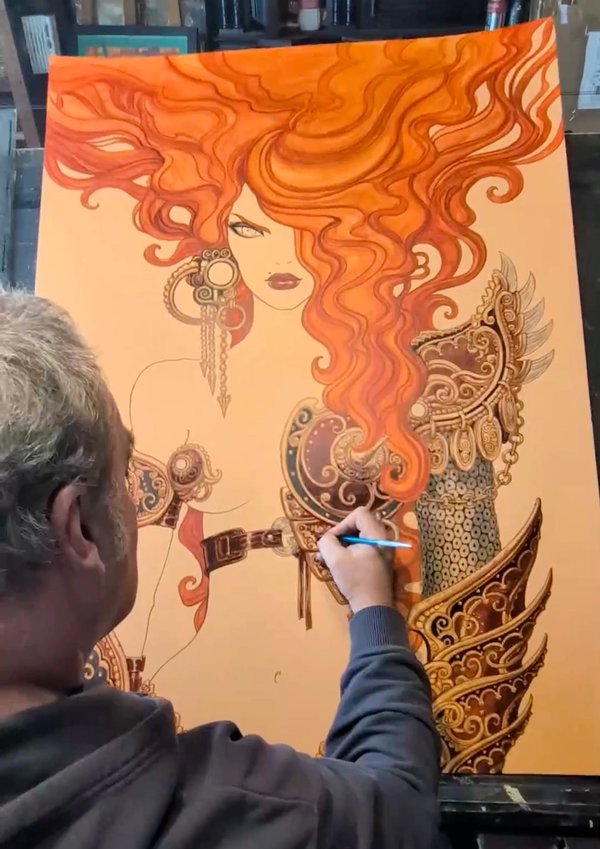 Olivier Ledroit travaille sur une illustration d'une femme aux cheveux roux ondulés, portant une armure ornée. L'affiche de Trolls et Légendes 2026 prend vie.