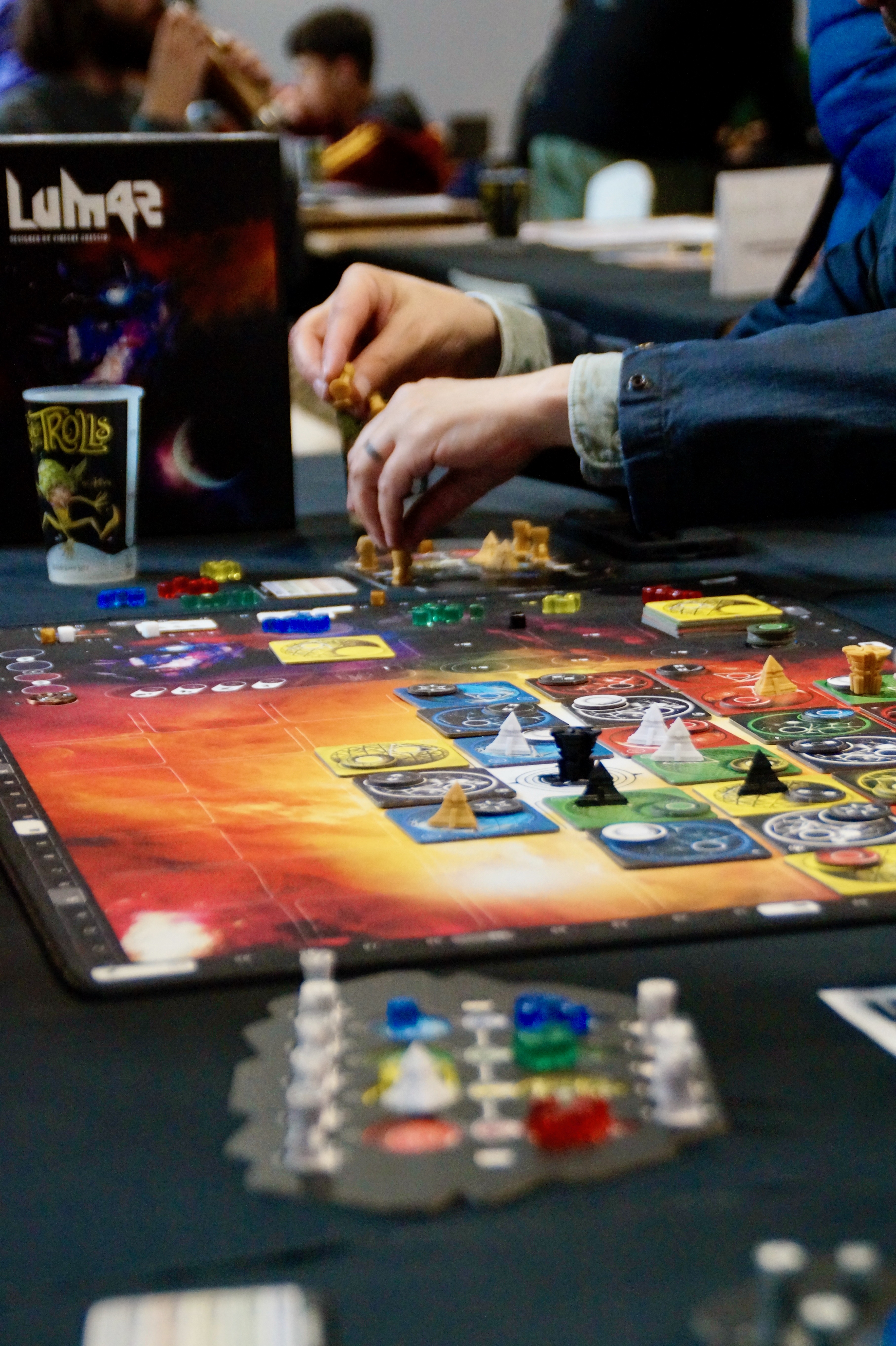 Personnes jouant à un jeu de plateau coloré sur une table lors d’un salon.